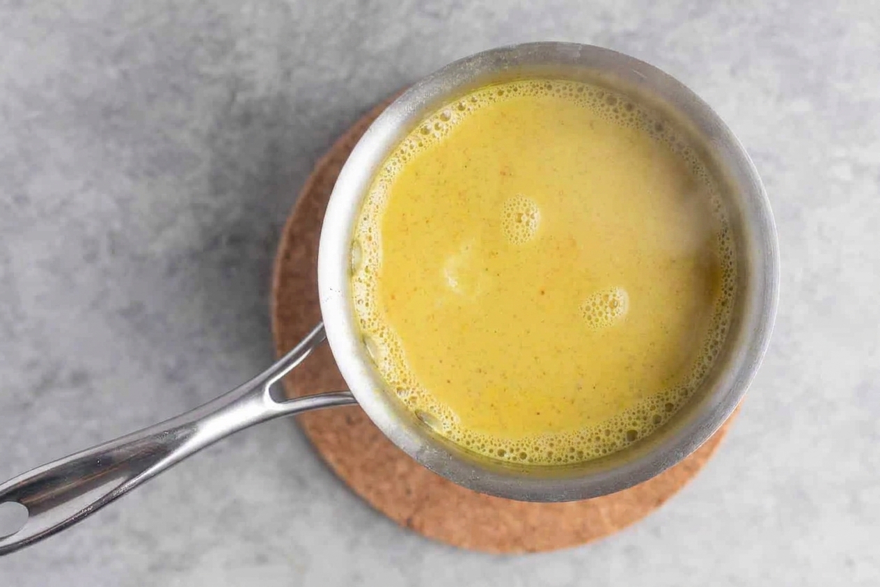 Golden turmeric milk gently simmering in a saucepan with small bubbles around the edges
