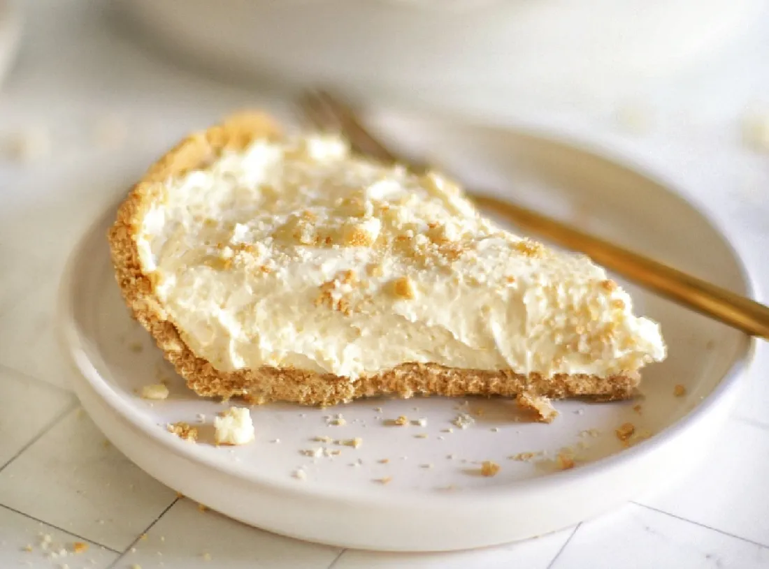 Graham crackers, melted butter, granulated sugar, cream cheese, powdered sugar, whipped topping, and a can of cherry pie filling arranged on a light kitchen counter