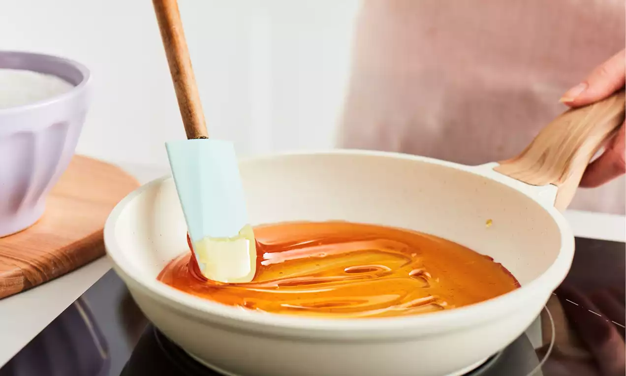 Granulated sugar melting into amber caramel in a small saucepan on a stovetop