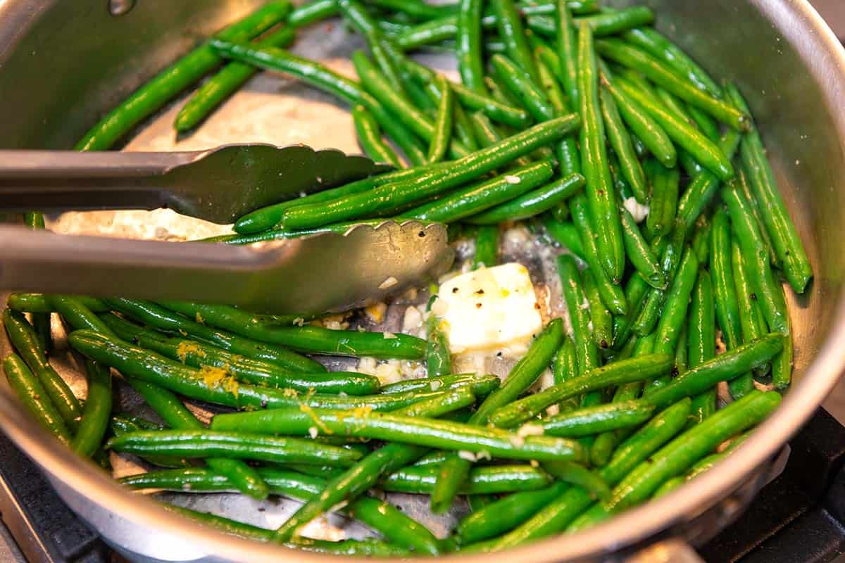 Green beans being tossed in a skillet with melted garlic butter