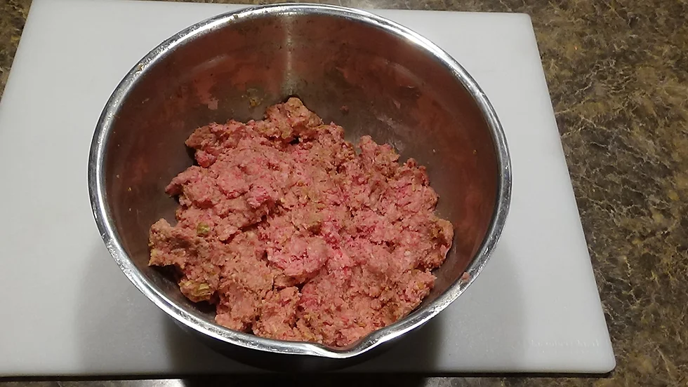 Ground beef in a large bowl with onion soup mix, breadcrumbs, eggs, and milk added on top before mixing