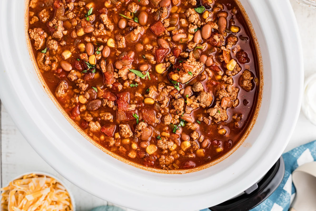 Ground turkey, canned beans, diced tomatoes, onion, garlic, spices, and broth arranged on a kitchen counter ready for slow cooker prep