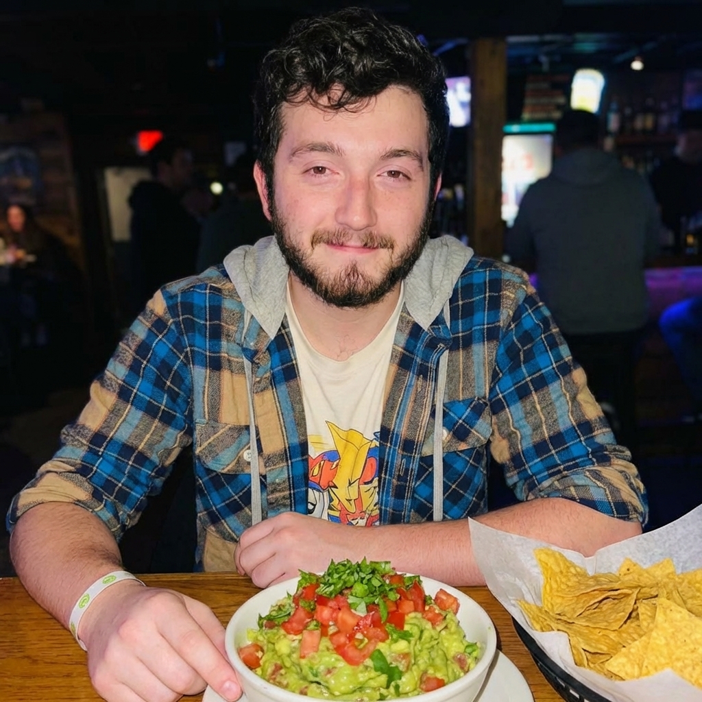 Guacamole in a bowl topped with diced tomato and cilantro with tortilla chips nearby