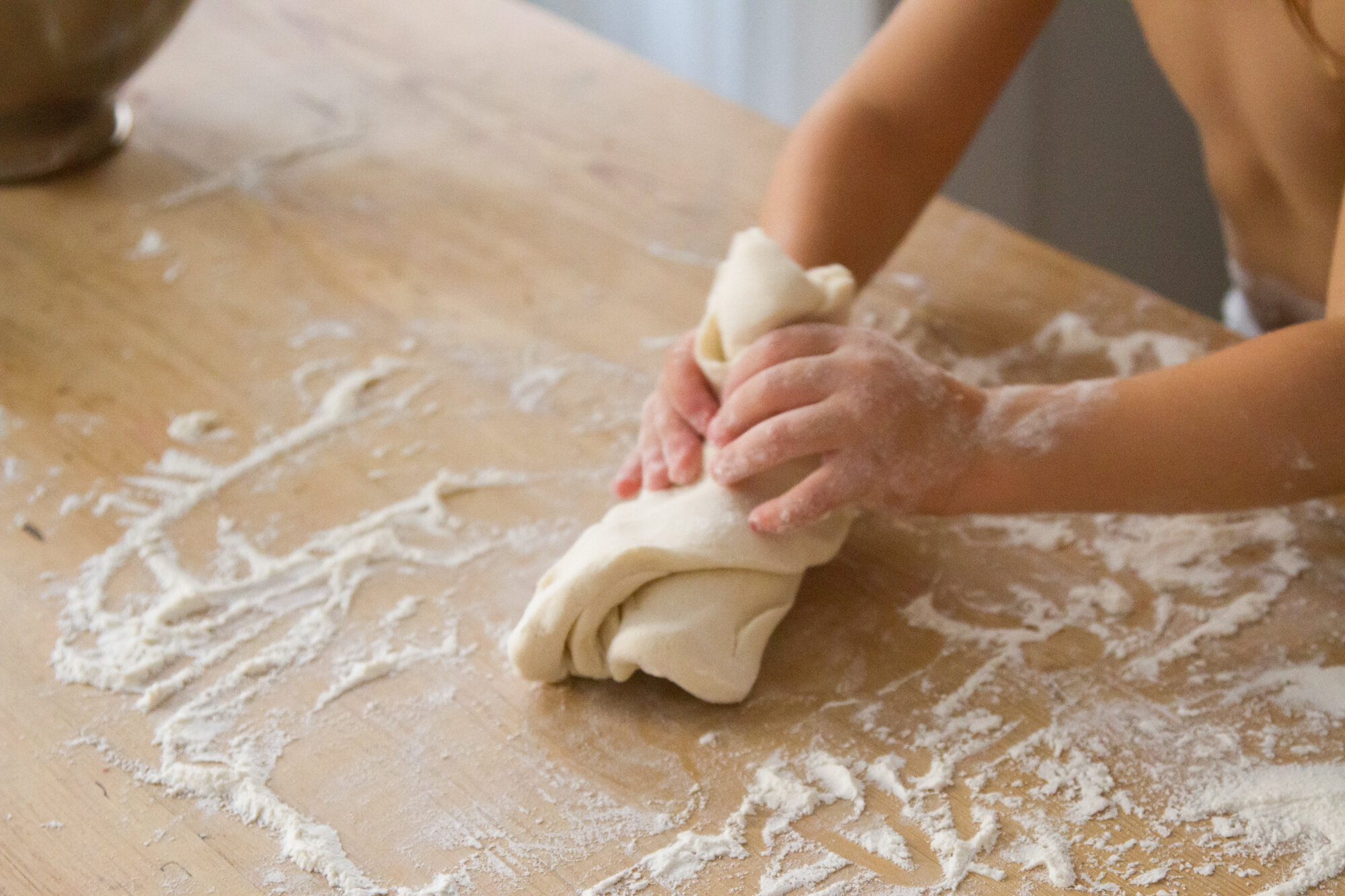 Hands kneading a smooth ball of salt dough on a lightly floured kitchen counter