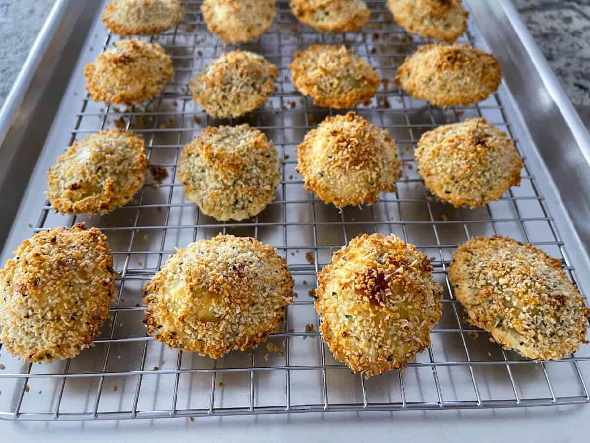 Hands pressing a ravioli into seasoned panko breadcrumbs on a kitchen counter