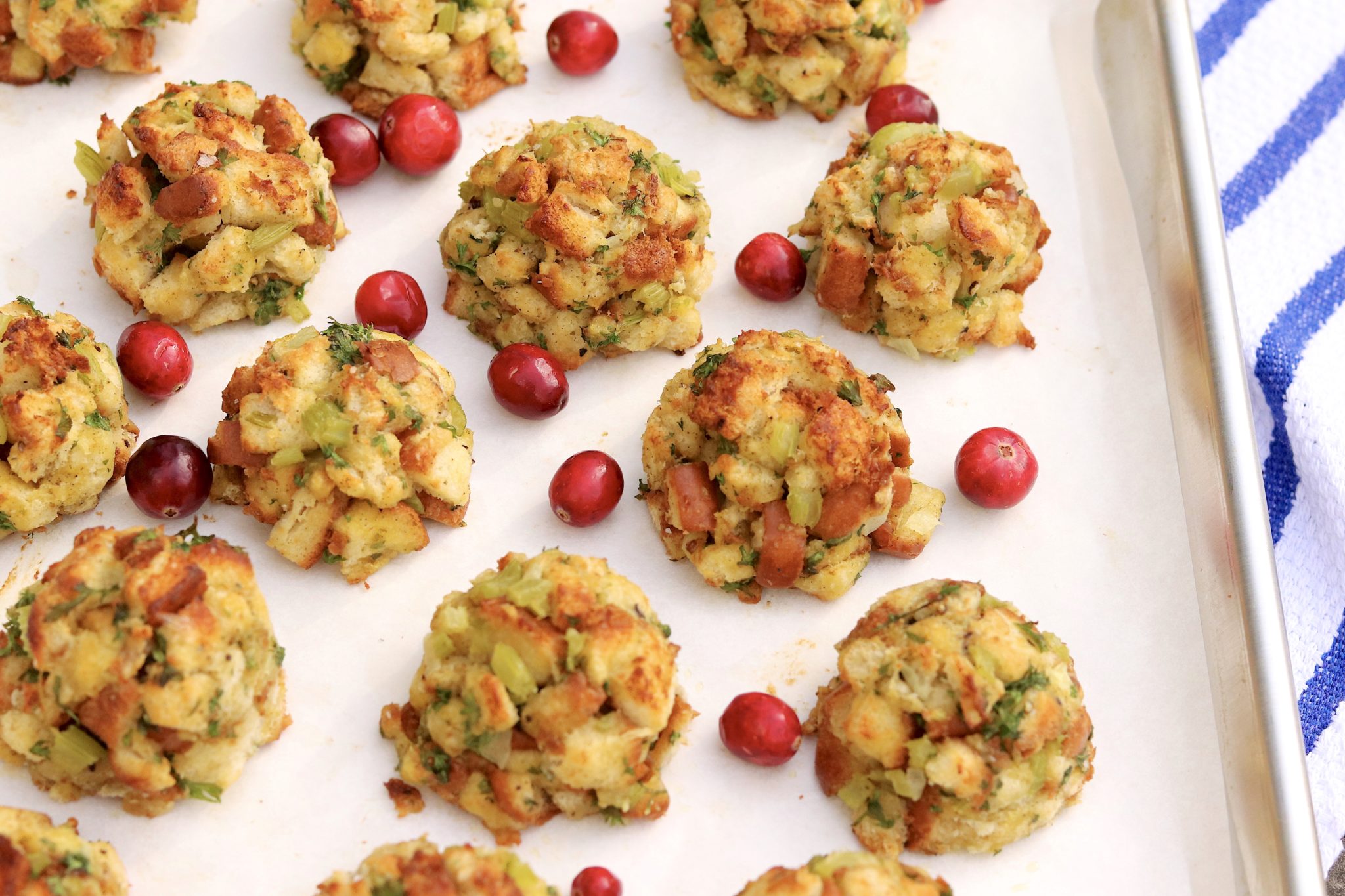 Hands roll stuffing mixture into a ball over a parchment-lined baking sheet on a kitchen counter