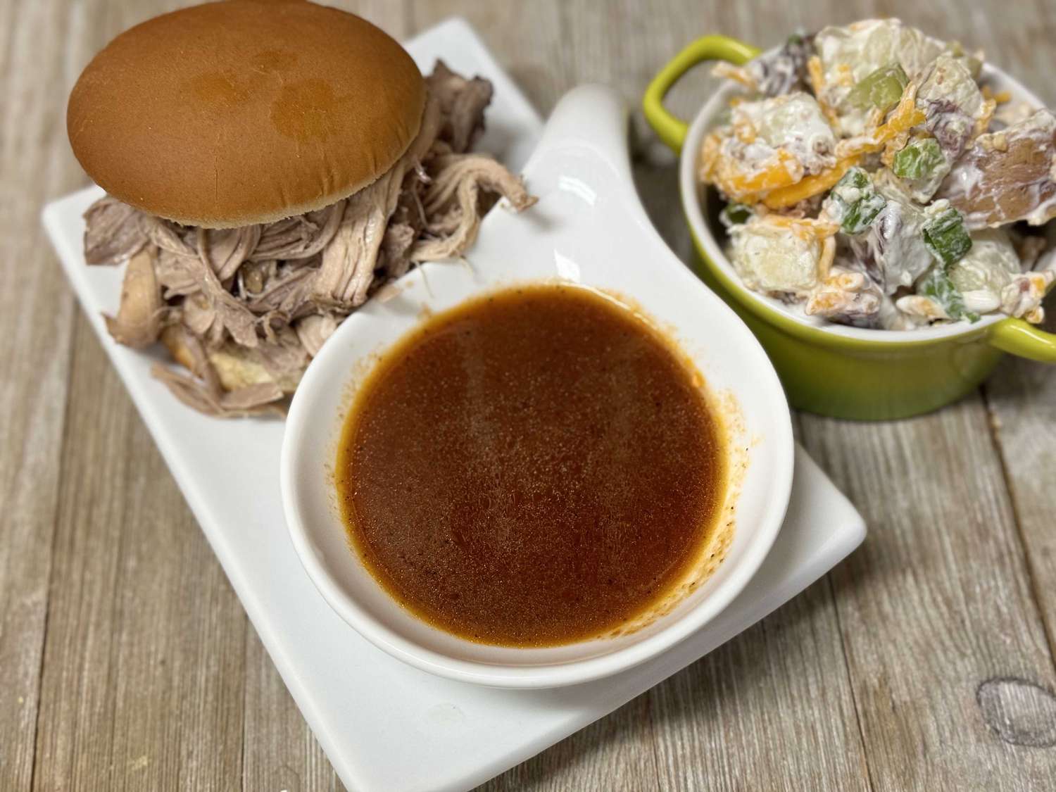 Hands whisking Carolina BBQ sauce in a medium mixing bowl on a wooden counter, sauce turning glossy as spices disperse