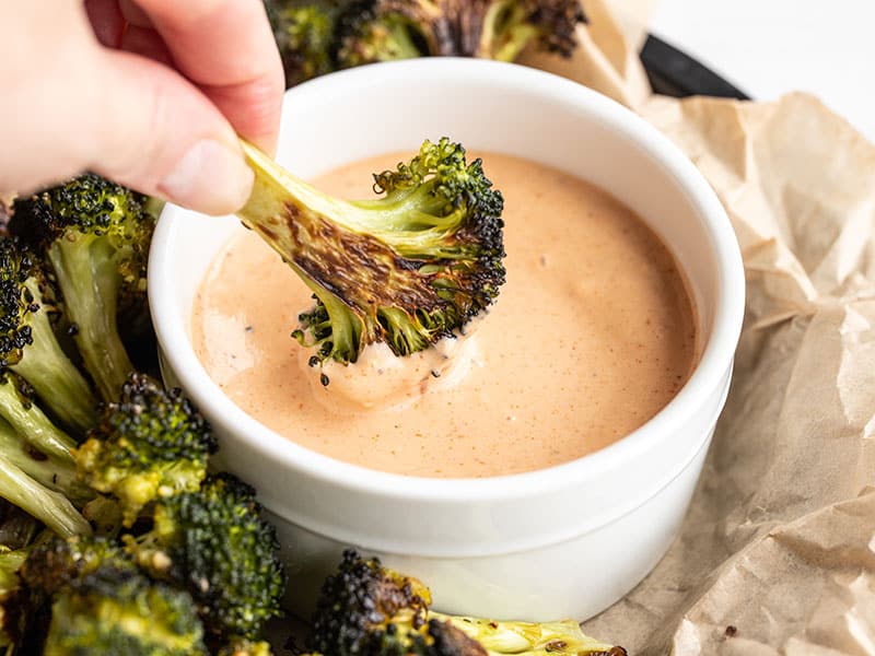 Hands whisking a creamy pink-orange dipping sauce in a small ceramic bowl on a kitchen counter