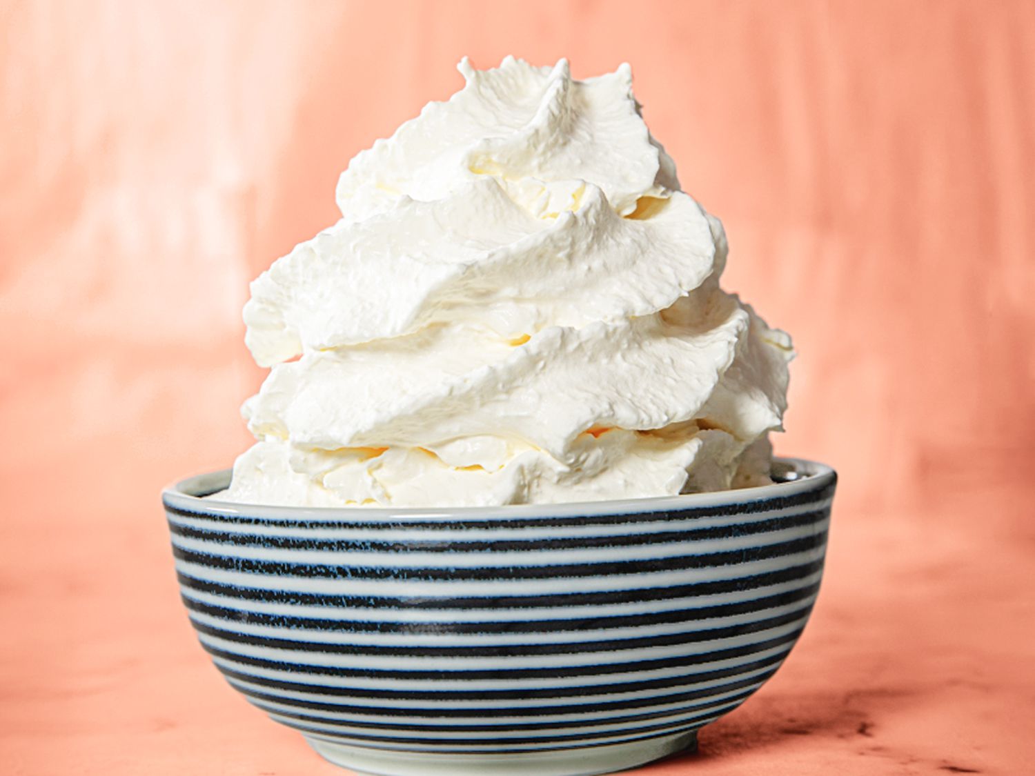 Heavy cream, powdered sugar, vanilla extract, and a chilled mixing bowl arranged on a clean kitchen counter in natural light
