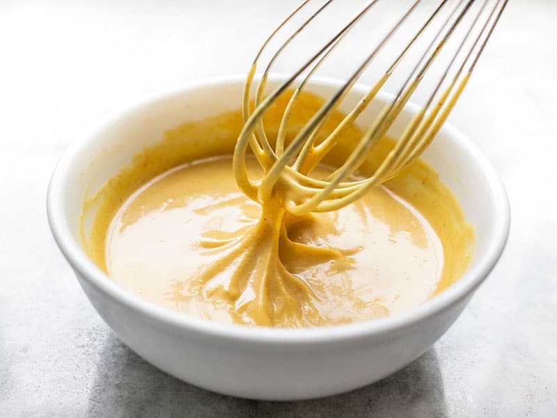 Honey, Dijon mustard, mayonnaise, apple cider vinegar, salt, and black pepper set out on a clean kitchen counter in consistent warm lighting