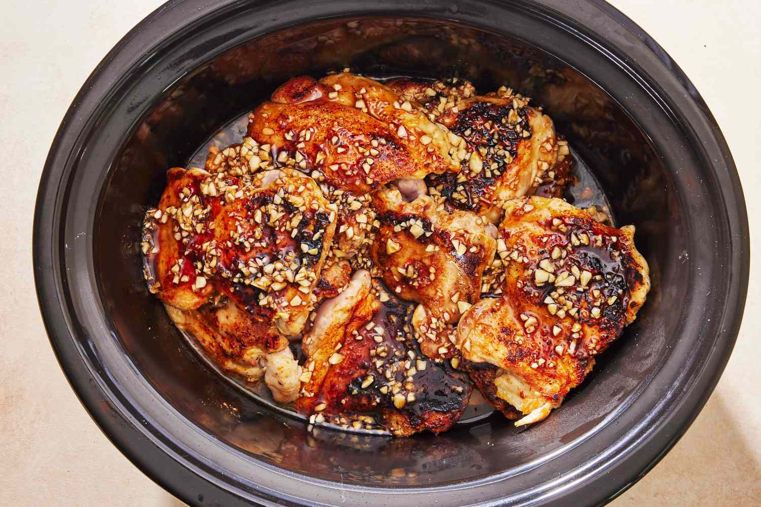 Honey garlic chicken thighs in a slow cooker with a glossy sauce, served over rice with scallions