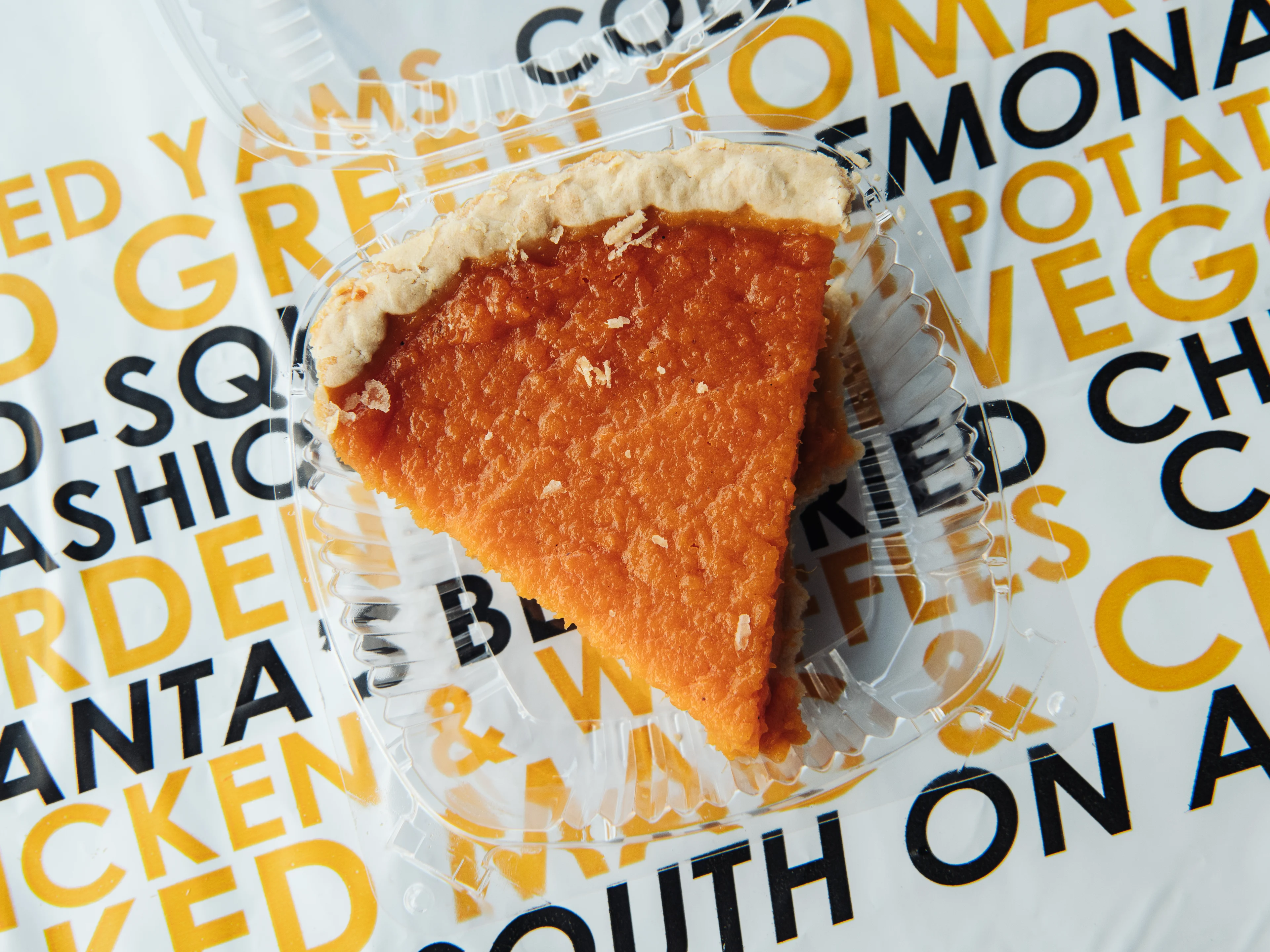 Individual slices of sweet potato pie stored in a glass food container with a snap-on lid on a kitchen counter
