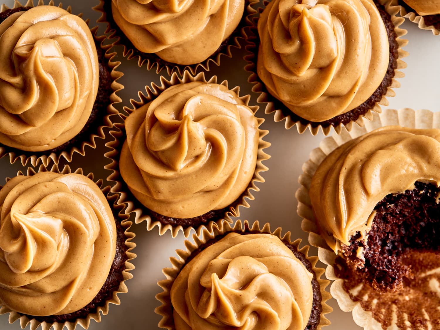 Ingredients for peanut butter frosting laid out on a neutral kitchen counter including peanut butter, powdered sugar, butter, vanilla, milk, and a pinch bowl of salt