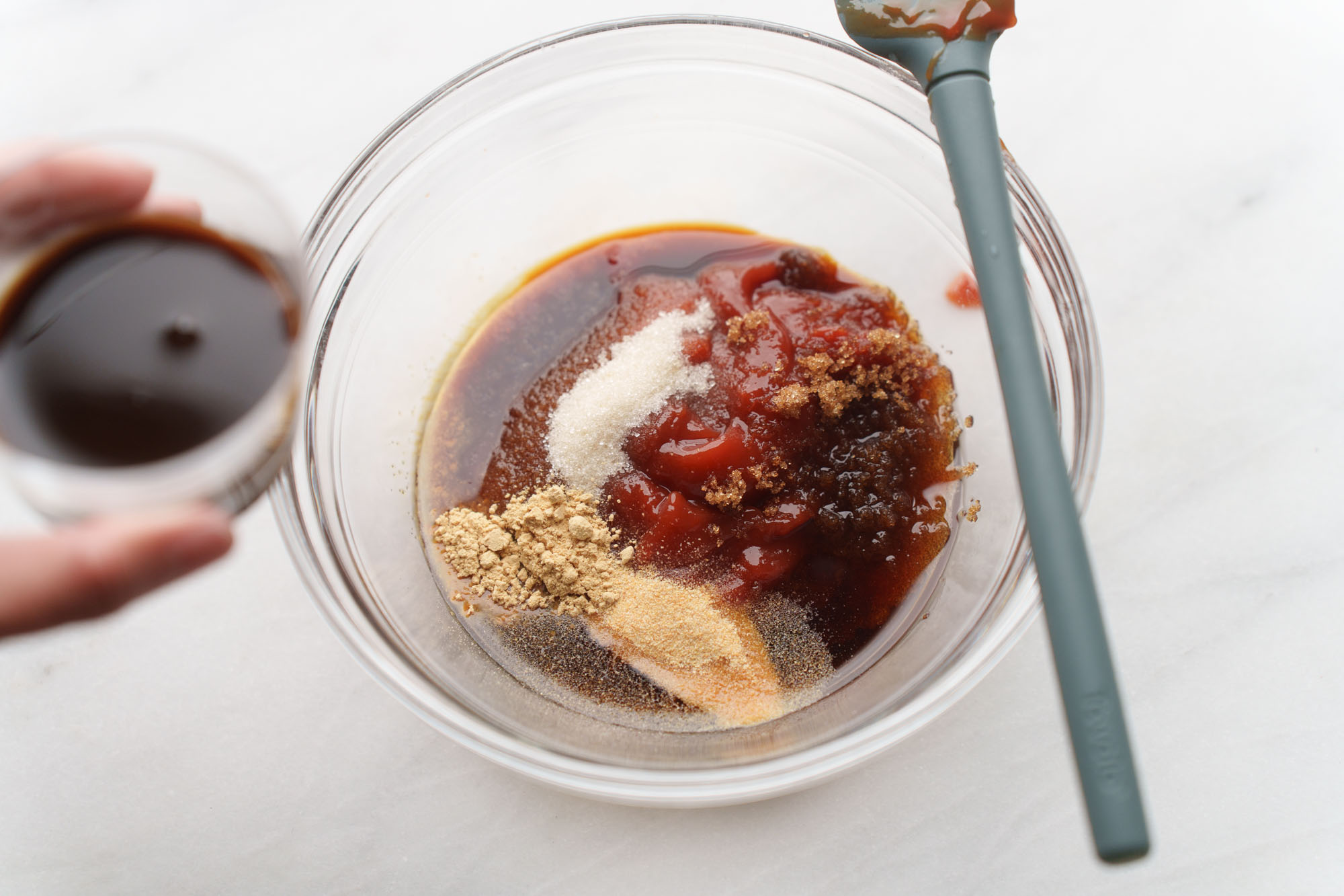 Katsu sauce ingredients being whisked together in a small white bowl on a kitchen counter