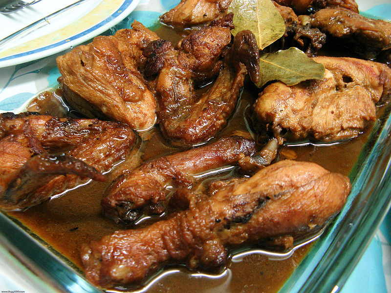 Leftover chicken adobo stored in a clear airtight container with sauce and bay leaves
