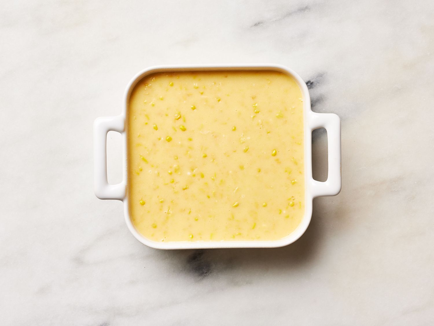 Leftover corn pudding portioned into a clear airtight container on a kitchen counter, ready for the refrigerator
