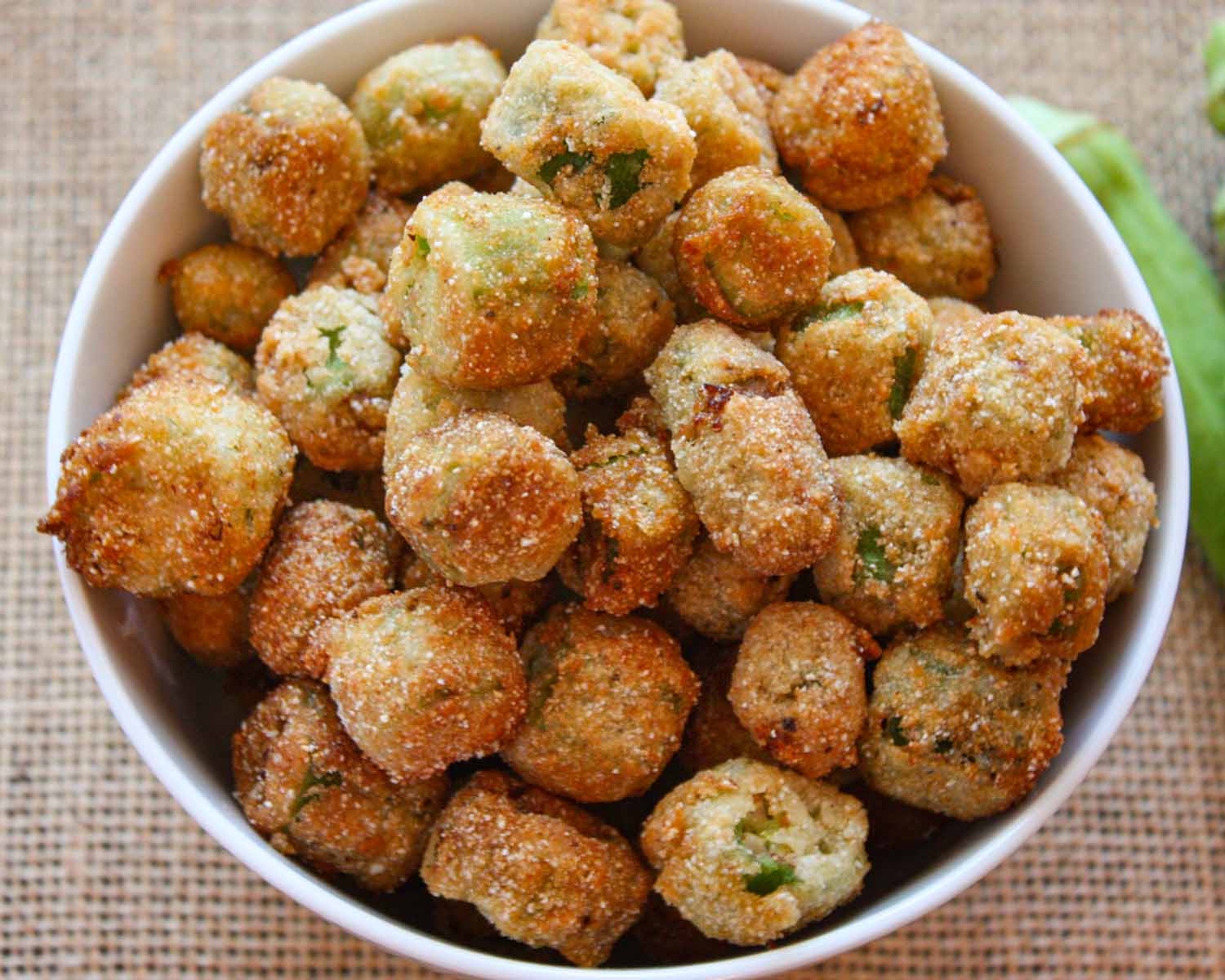 Leftover fried okra spread in a single layer on a parchment-lined sheet pan ready to reheat in the oven