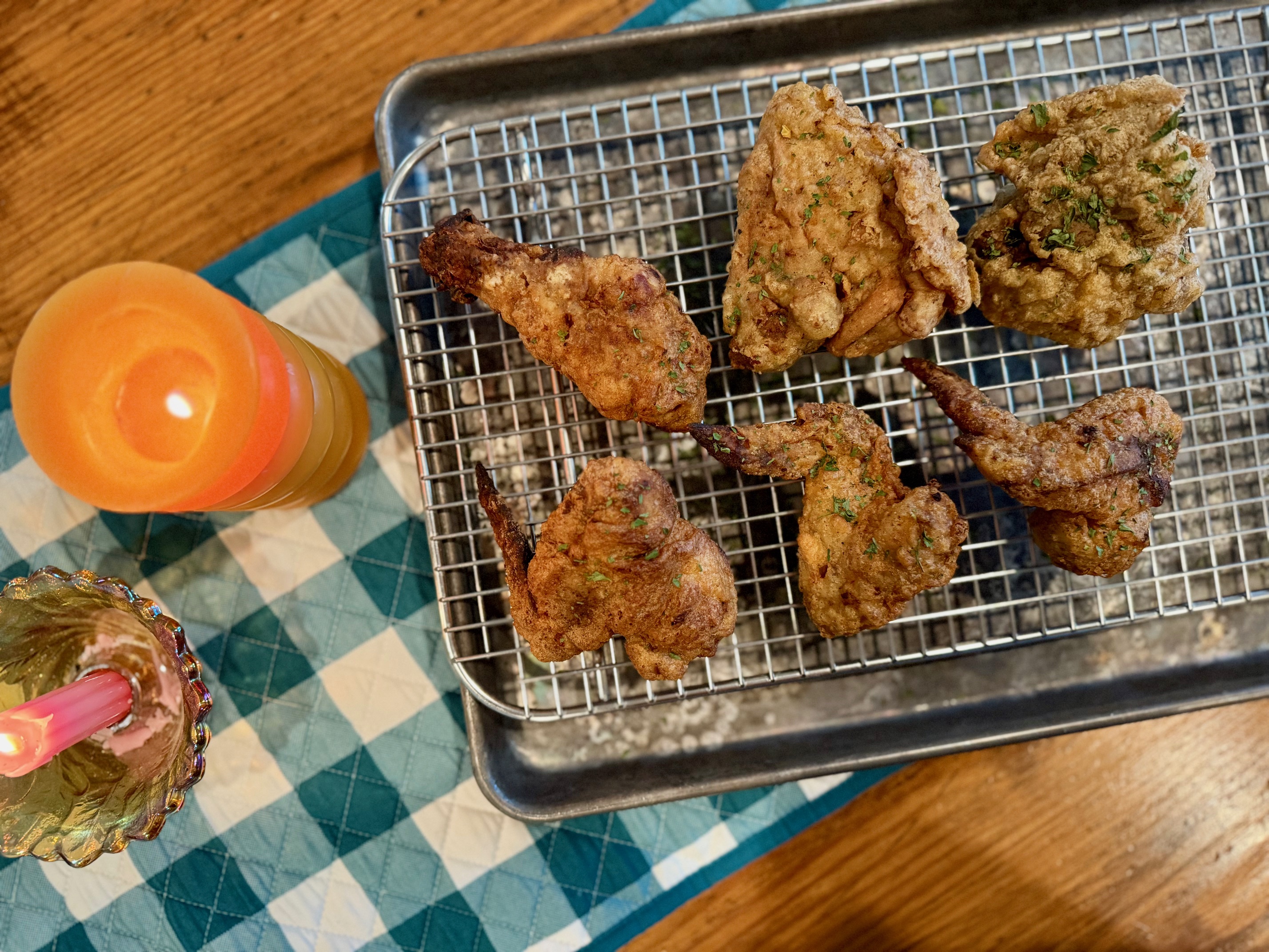 Leftover oven fried chicken reheating on a wire rack set over a sheet pan in a home oven, showing crisp coating starting to re-crunch