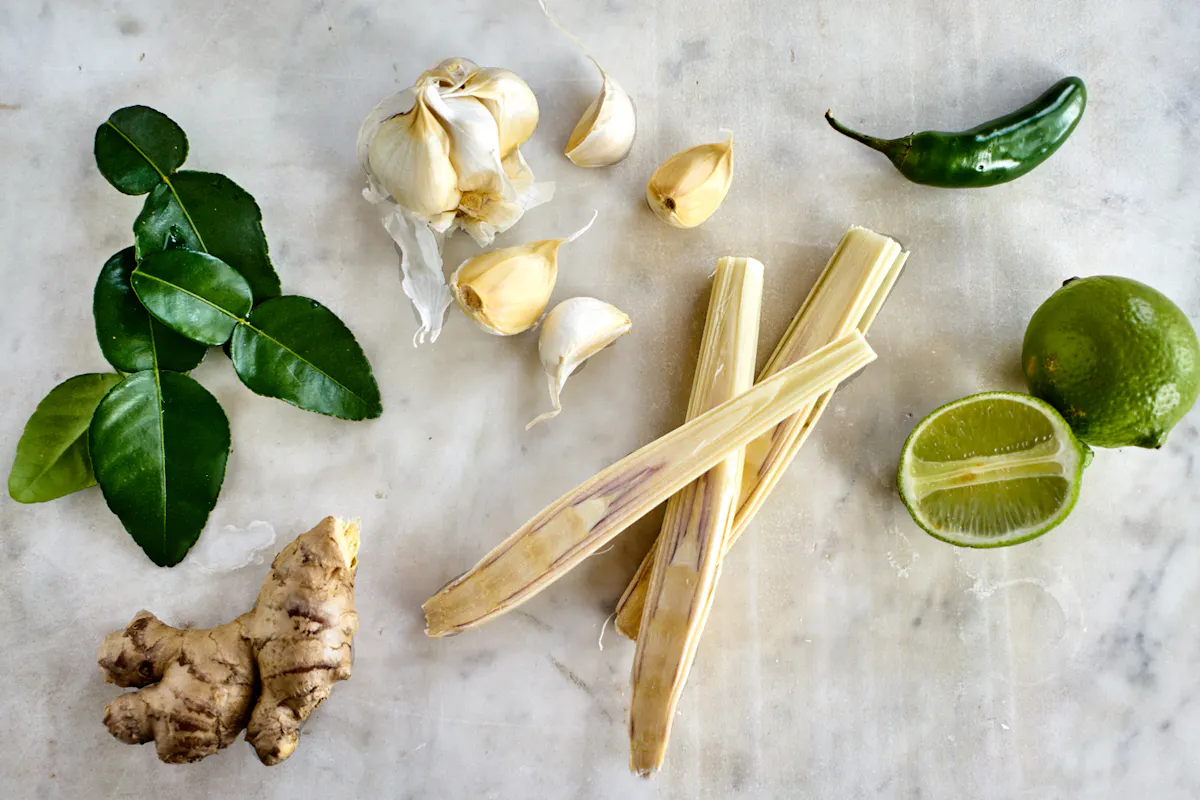 Lemongrass pieces and makrut lime leaves warming in a pot before liquid is added