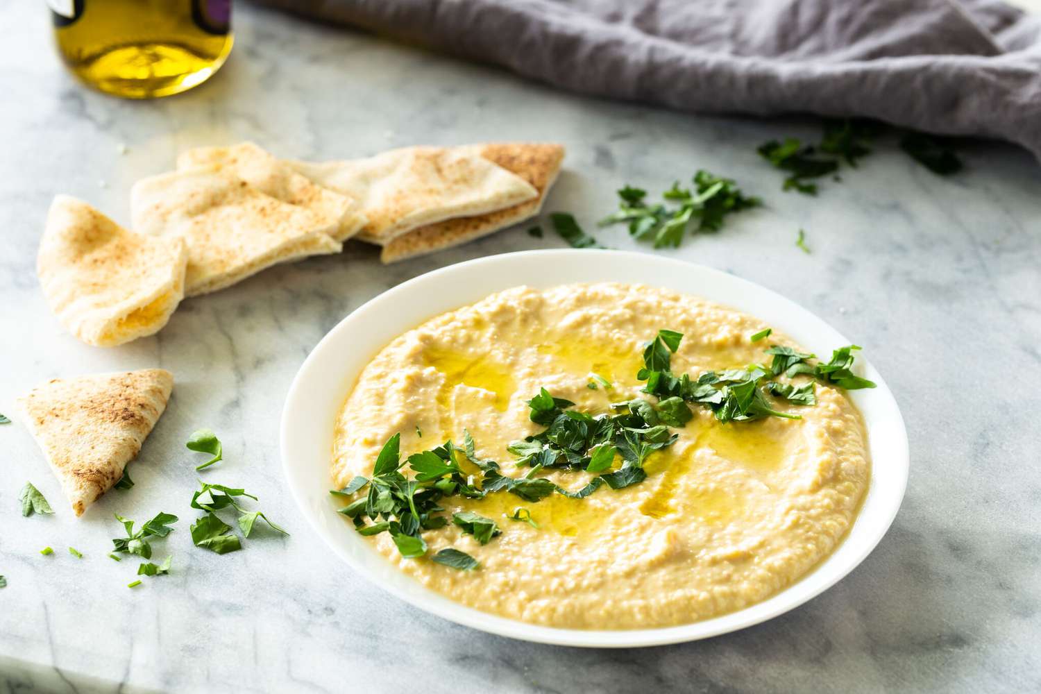 Measured chickpeas, tahini, lemon juice, garlic, olive oil, cumin, and salt arranged in small bowls on a bright kitchen counter