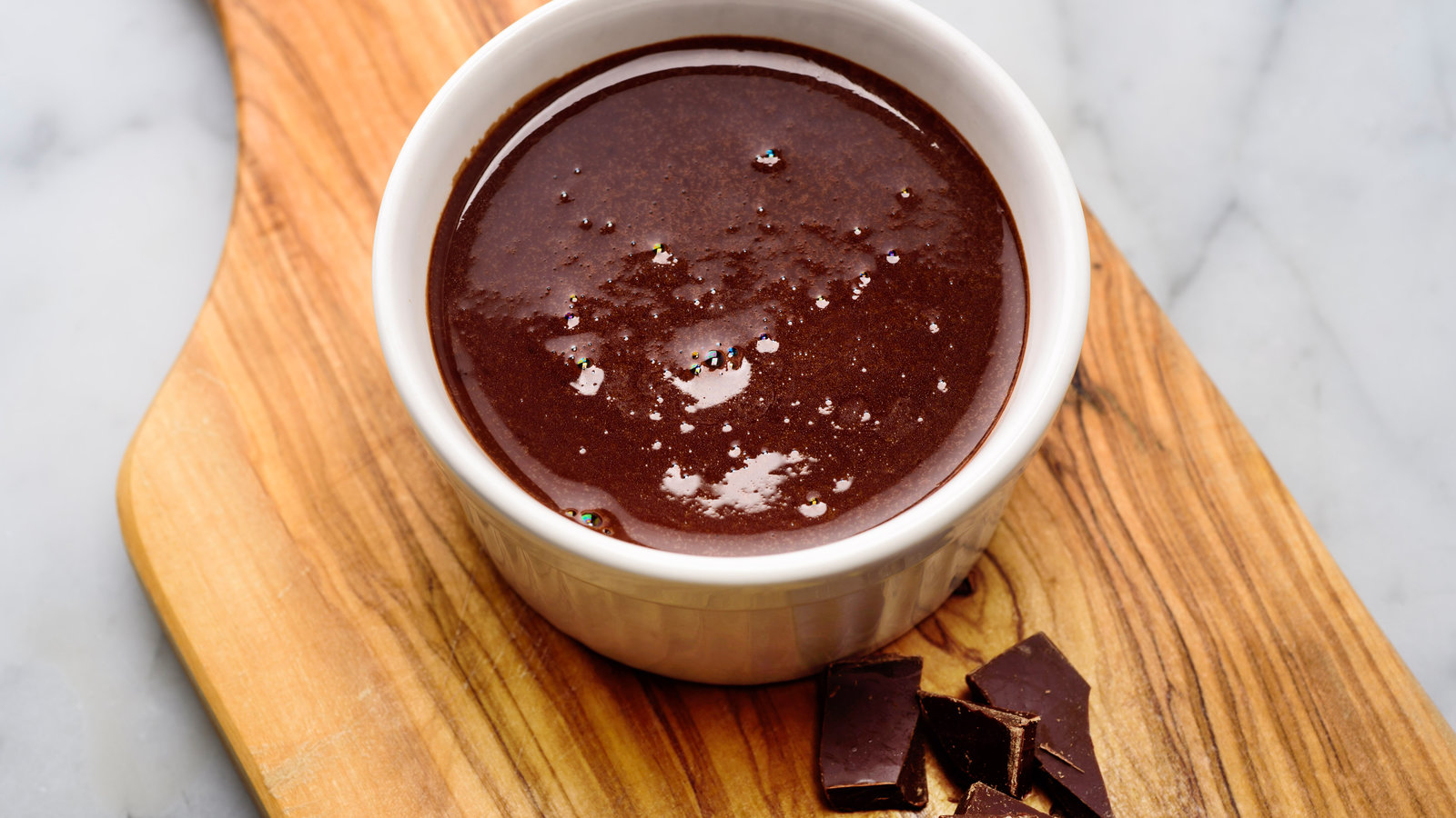 Measured cocoa powder, granulated sugar, butter, vanilla extract, and salt arranged on a light kitchen counter with small bowls and measuring spoons