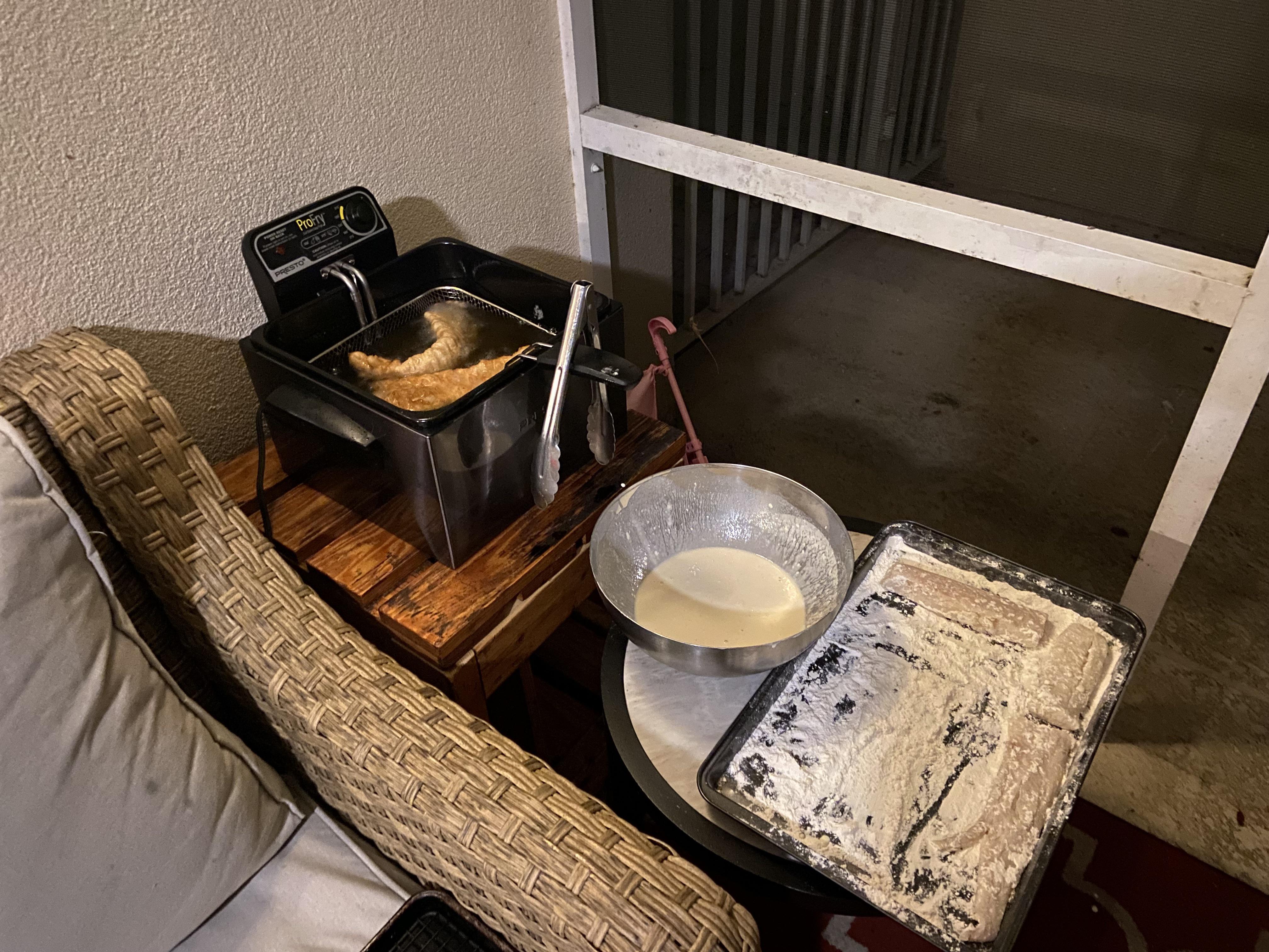 Measured ingredients for beer-battered fried cod arranged on a kitchen counter including cod fillets, flour, cornstarch, beer, spices, lemon, and mayonnaise