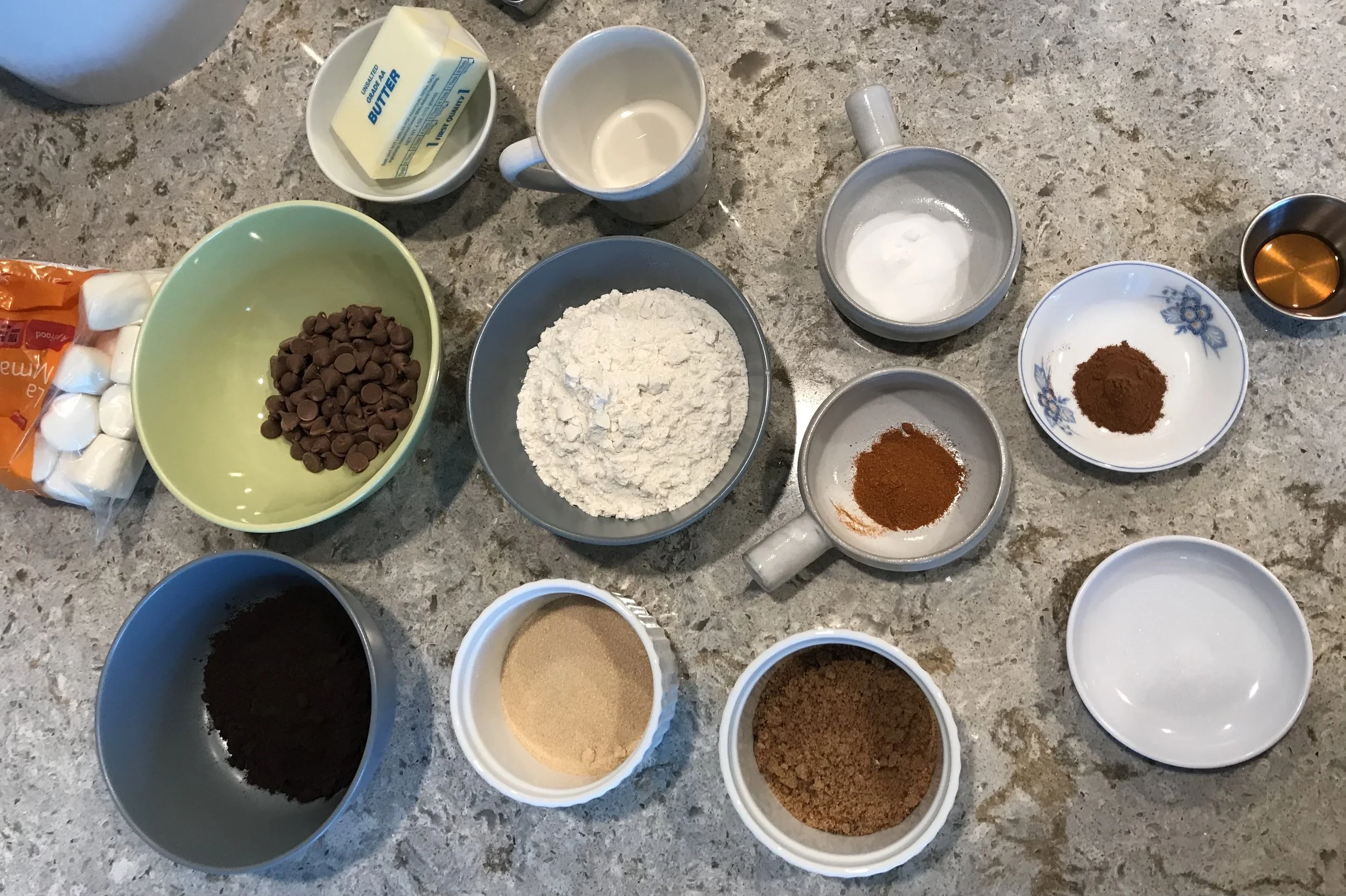 Measured ingredients for chocolate pound cake including cocoa powder, flour, butter, sugar, eggs, and sour cream arranged on a light stone countertop