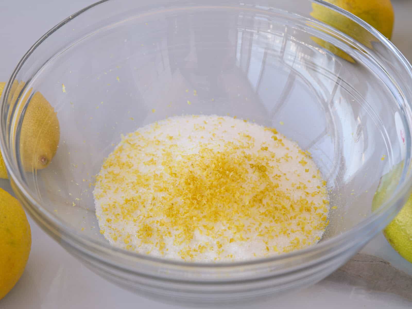 Measured ingredients for dandelion jelly including lemon zest, lemon juice, sugar, and powdered pectin arranged on a kitchen counter