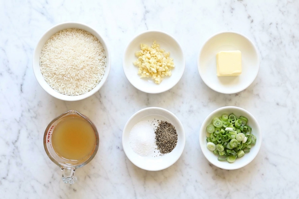 Measured ingredients for garlic rice on a kitchen counter including rinsed jasmine rice, minced garlic, butter, broth, salt, pepper, and sliced scallions