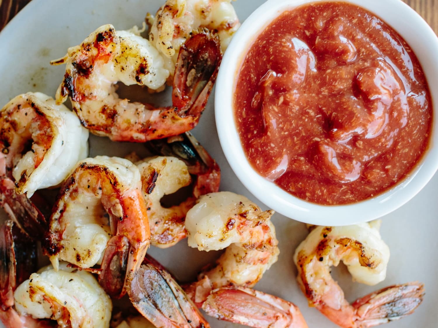 Measured ingredients for shrimp cocktail sauce including ketchup, prepared horseradish, lemon, Worcestershire sauce, hot sauce, salt, and pepper arranged on a light kitchen counter