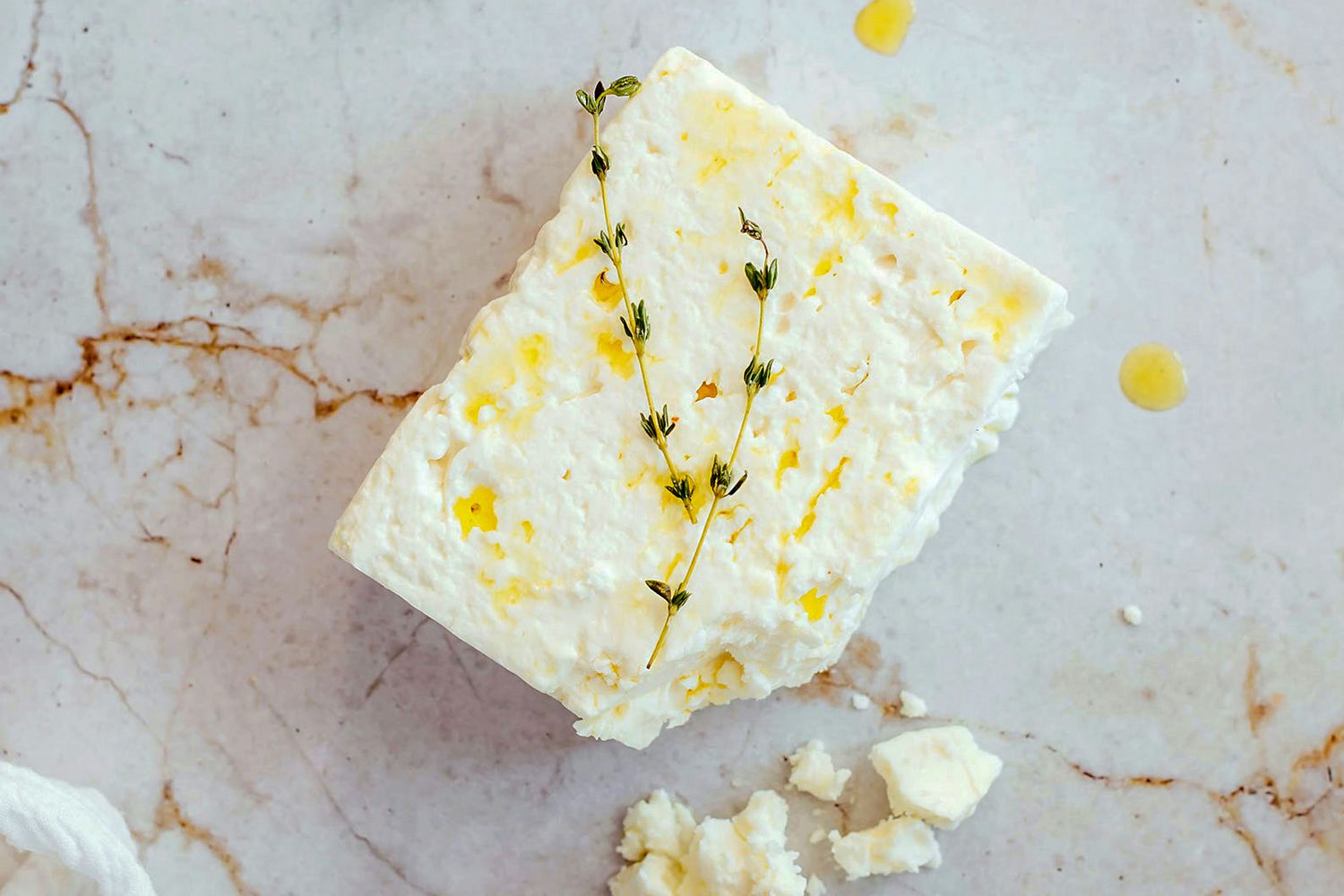 Measured ingredients for whipped feta including crumbled feta, Greek yogurt, lemon, garlic, olive oil, and herbs arranged on a clean kitchen counter