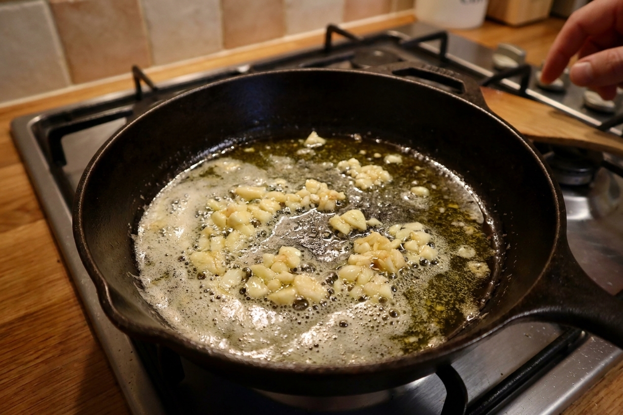 Minced garlic gently sizzling in melted butter and olive oil in a skillet on a home stove