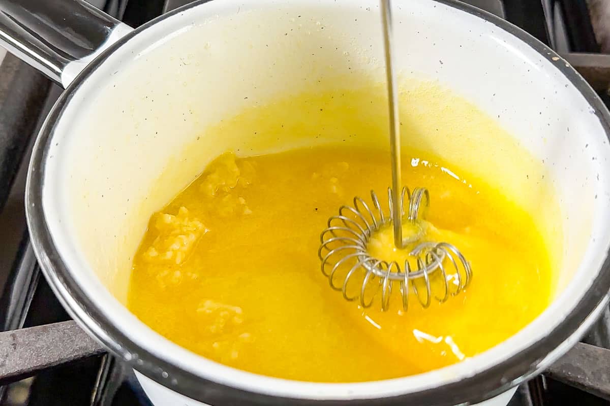 Minced garlic sizzling gently in melted butter in a small stainless steel saucepan on a home stove