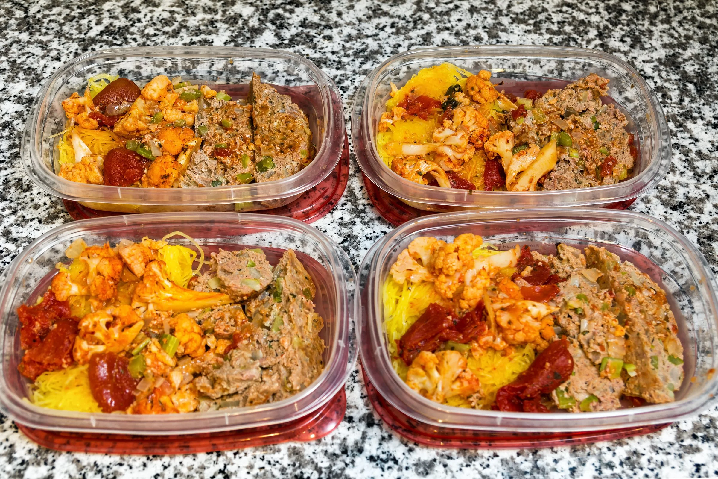 Mini meatloaves stored in a glass meal prep container with a little extra glaze, on a clean kitchen counter