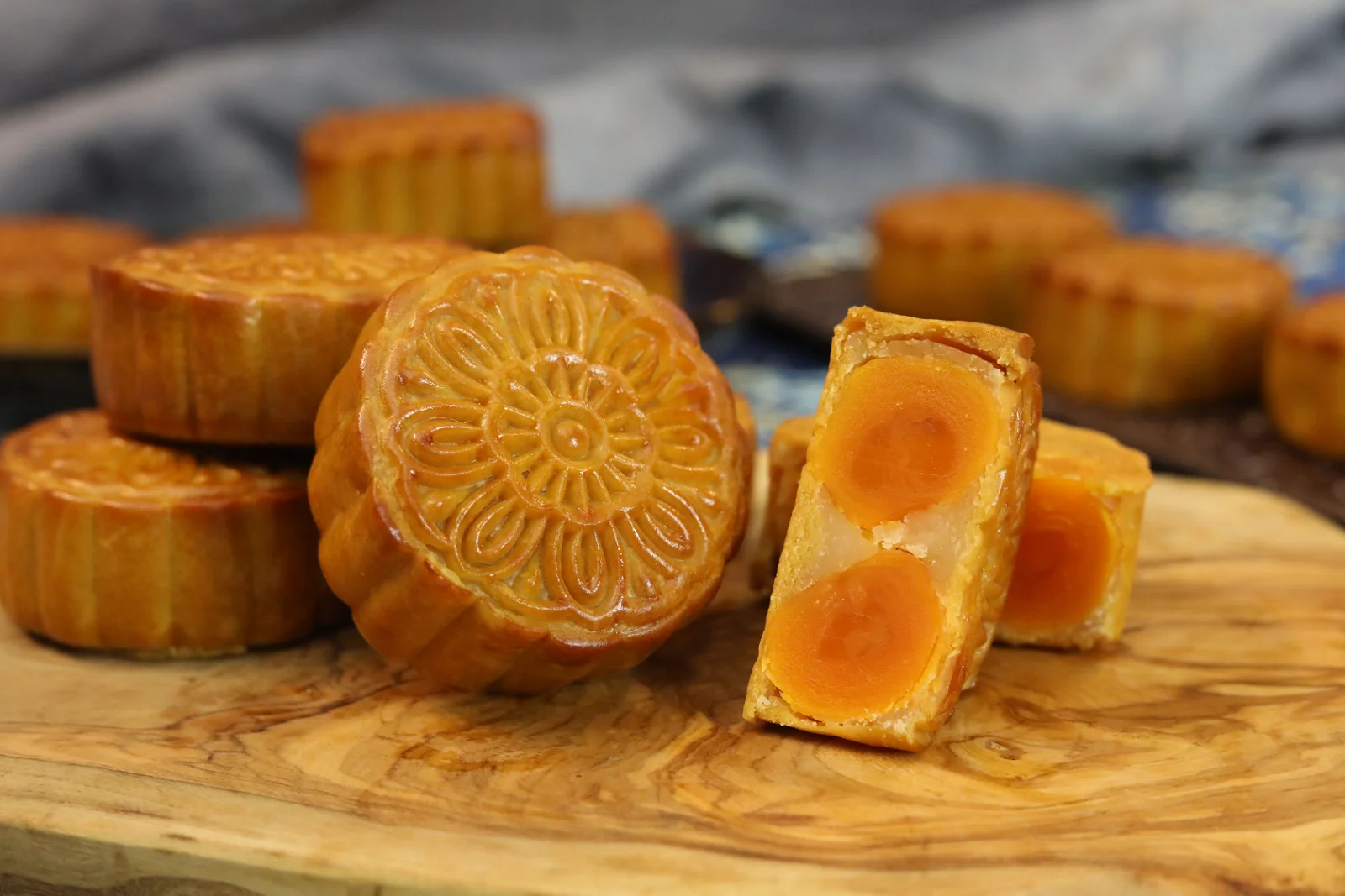 Mooncake ingredients arranged on a light kitchen countertop including golden syrup, all purpose flour, oil, alkaline water, lotus seed paste, egg yolks, and a mooncake mold