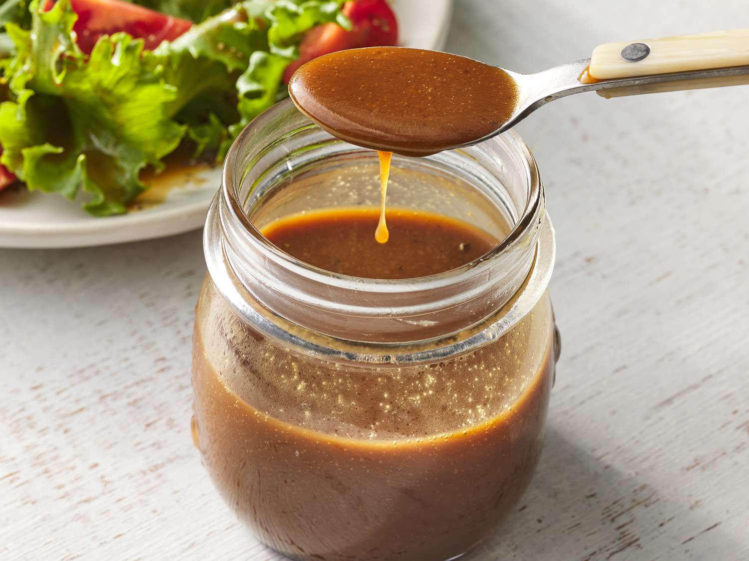 Olive oil, red wine vinegar, Dijon mustard, honey, garlic, salt, and black pepper arranged on a bright kitchen counter