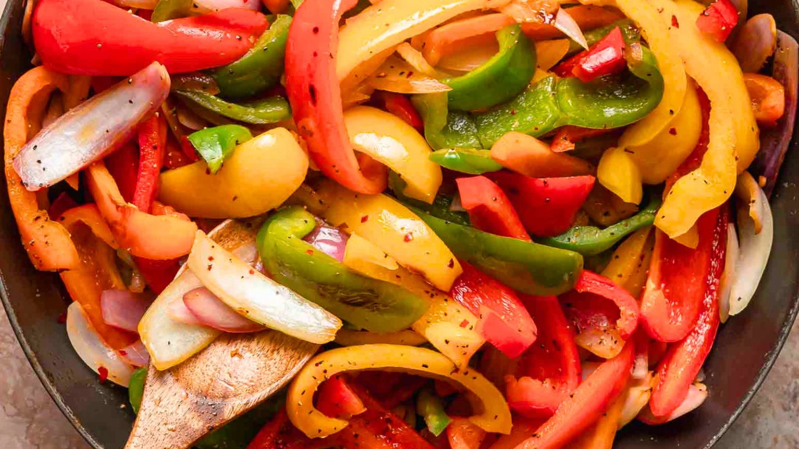 Onion and green bell pepper sautéing in olive oil in a saucepan on a stovetop