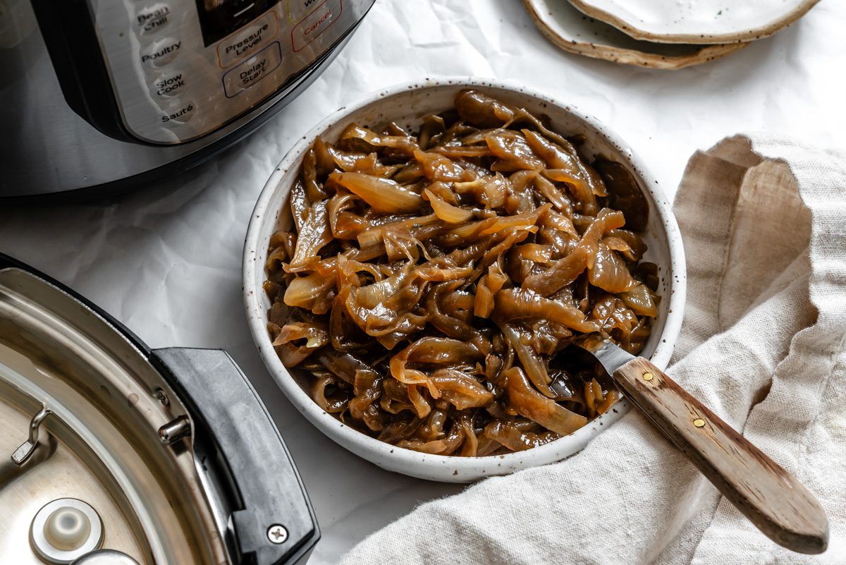 Onion wedges and smashed garlic cloves layered in the bottom of a slow cooker insert