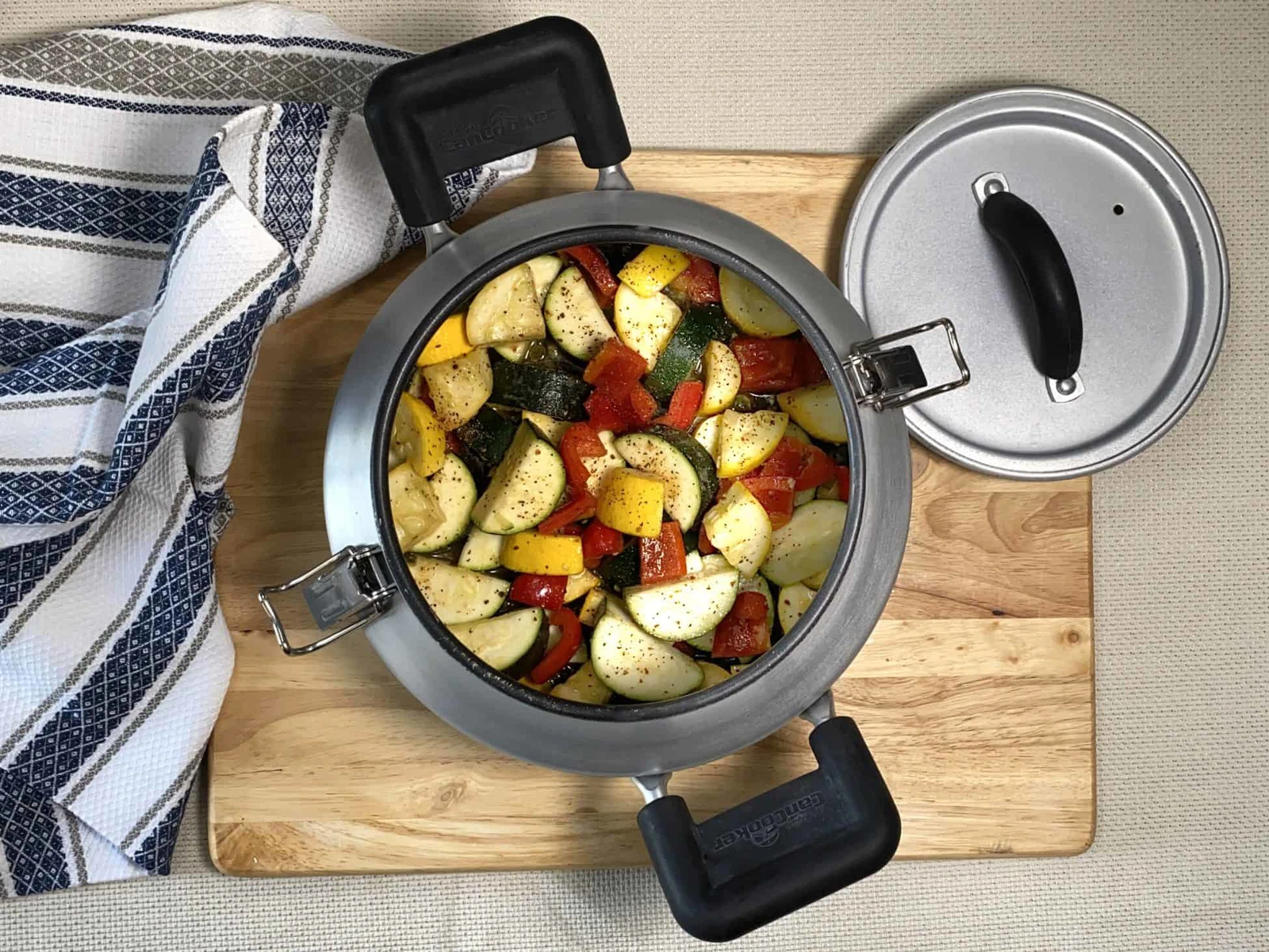 Onions, peppers, carrots, and celery sautéing in a Dutch oven on a stovetop with a wooden spoon stirring