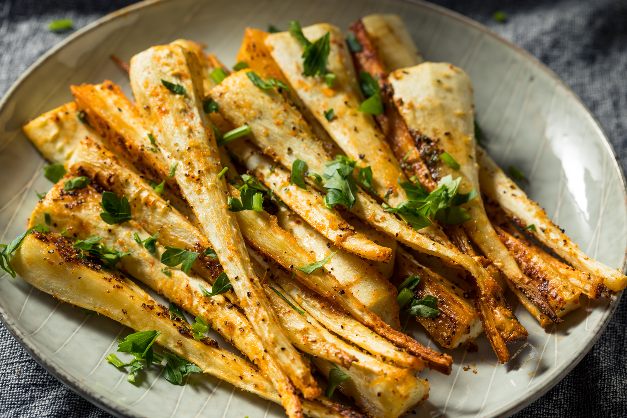 Parsnips with olive oil, salt, pepper, honey, lemon, and fresh thyme on a cutting board, ready to prep
