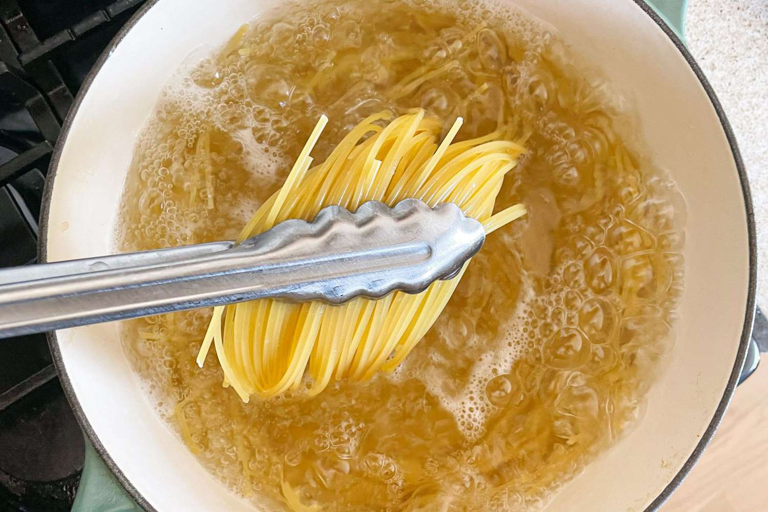 Pasta boiling in a large pot of salted water on a home stove with steam rising