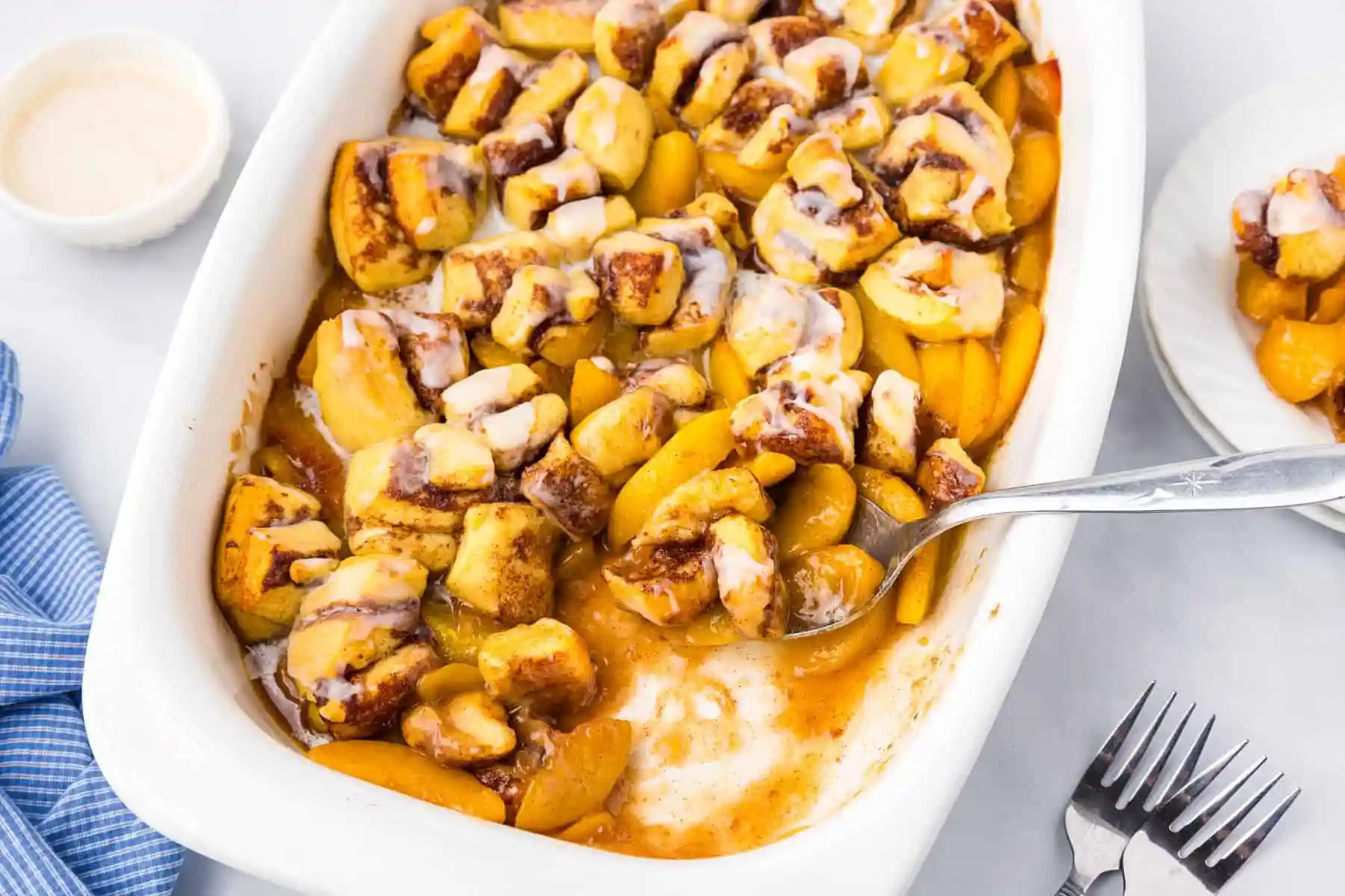 Peach slices tossed with cinnamon and brown sugar in a glass baking dish on a kitchen counter