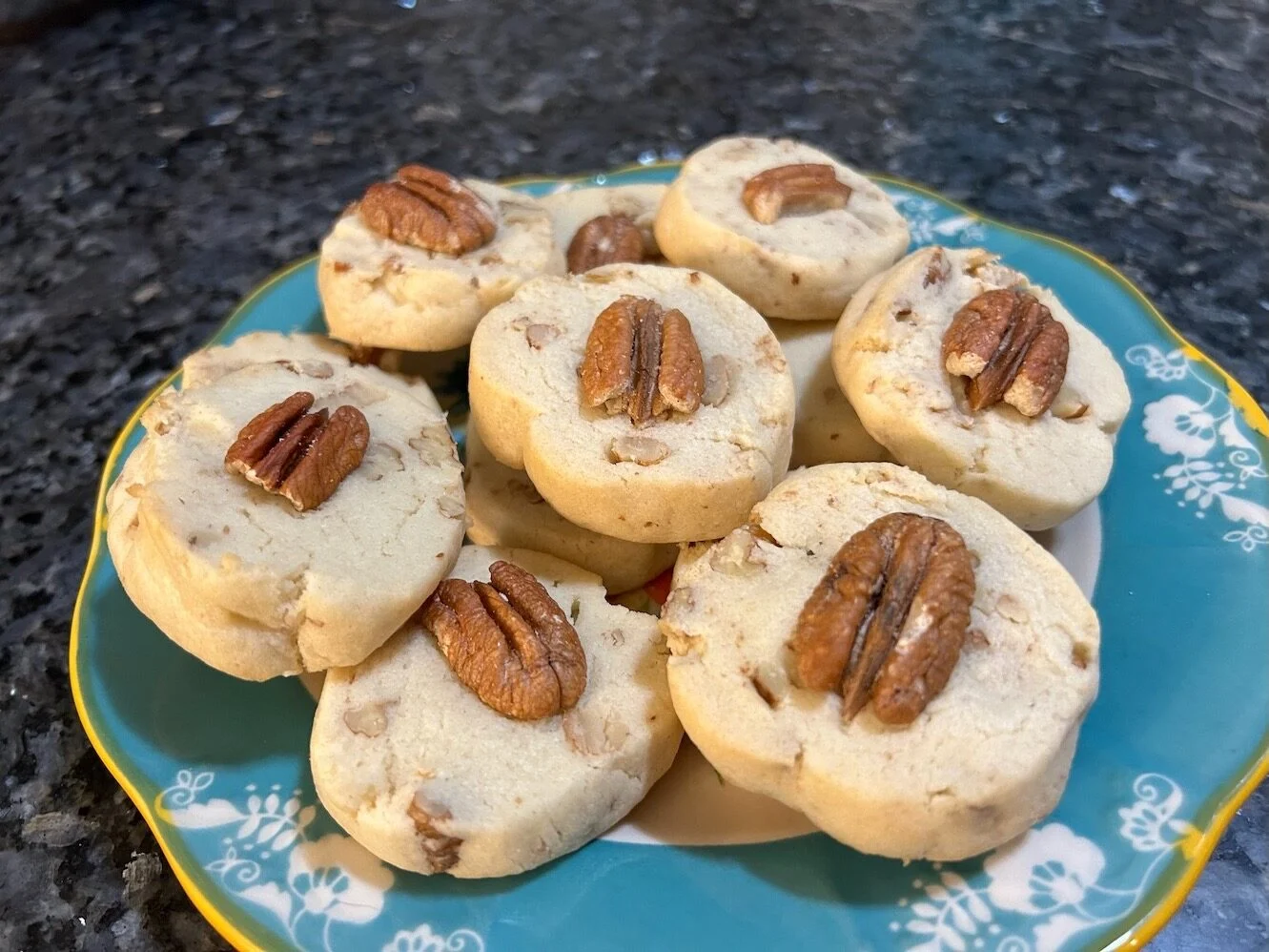 Pecan sandies cookies stacked inside a clear airtight container on a kitchen counter