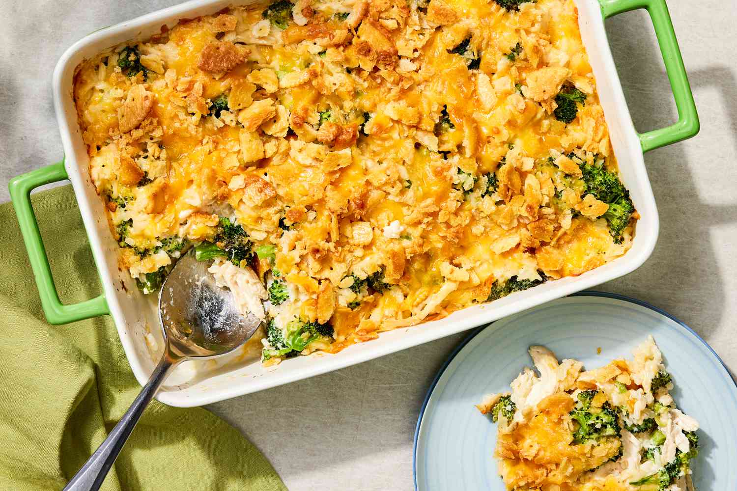 Portion of chicken and broccoli casserole in a glass meal prep container with a snap-on lid on a kitchen counter, showing creamy sauce and broccoli pieces