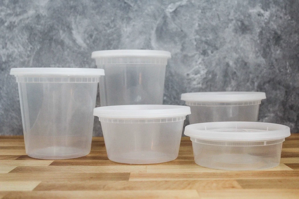 Portions of tomato soup in clear airtight containers on a kitchen counter, ready for meal prep storage