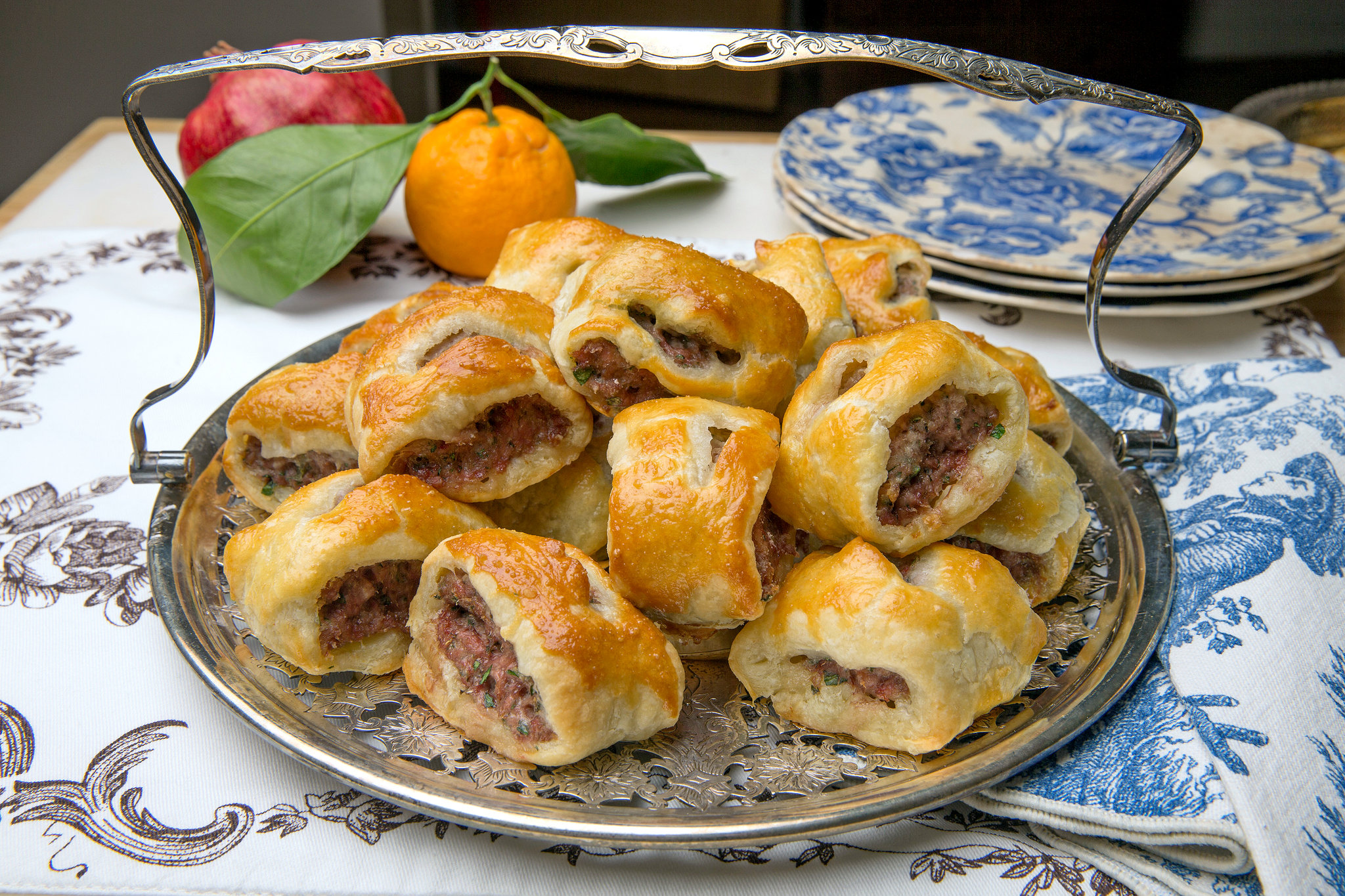 Puff pastry sheets, ground sausage, onion, garlic, herbs, egg, breadcrumbs, and seasonings arranged on a clean kitchen counter in consistent warm lighting