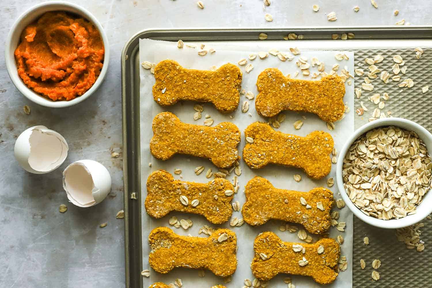 Pumpkin puree, natural peanut butter, eggs, oats, and whole wheat flour measured out for making dog treats