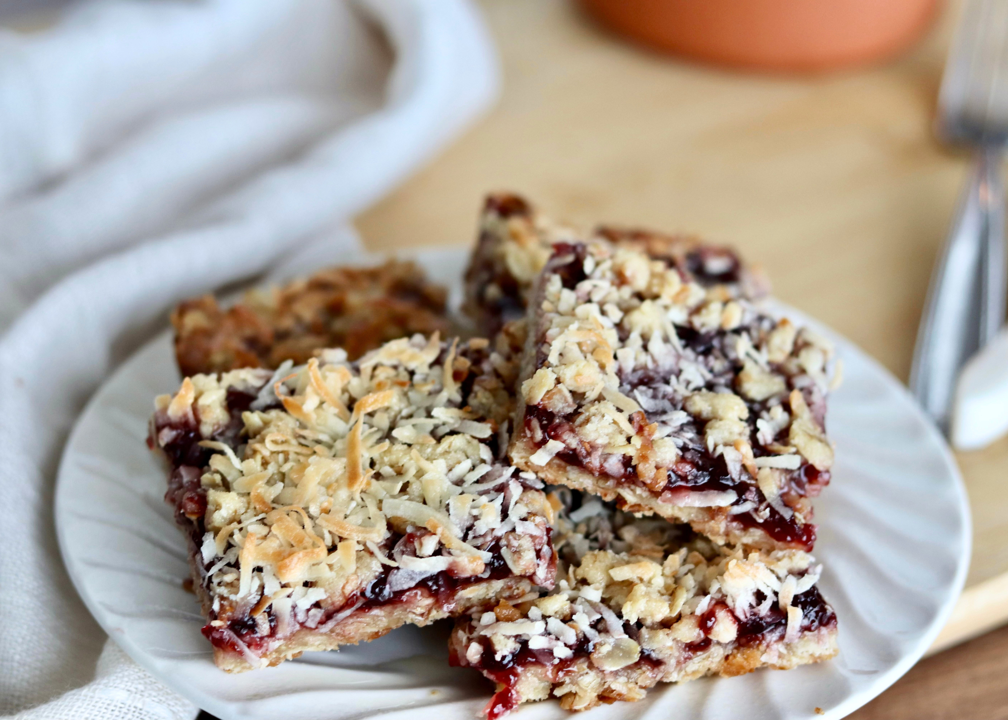 Raspberry jam, chocolate chips, and shredded coconut measured out in small bowls on a bright kitchen counter