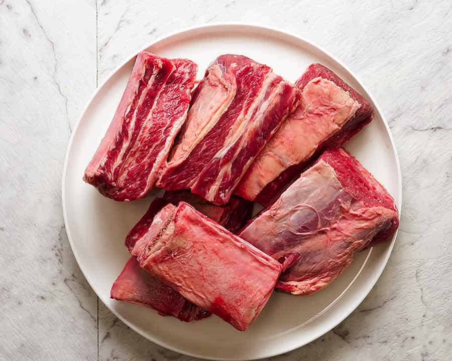 Raw English-cut beef short ribs arranged on a cutting board with visible marbling and thick bone sections