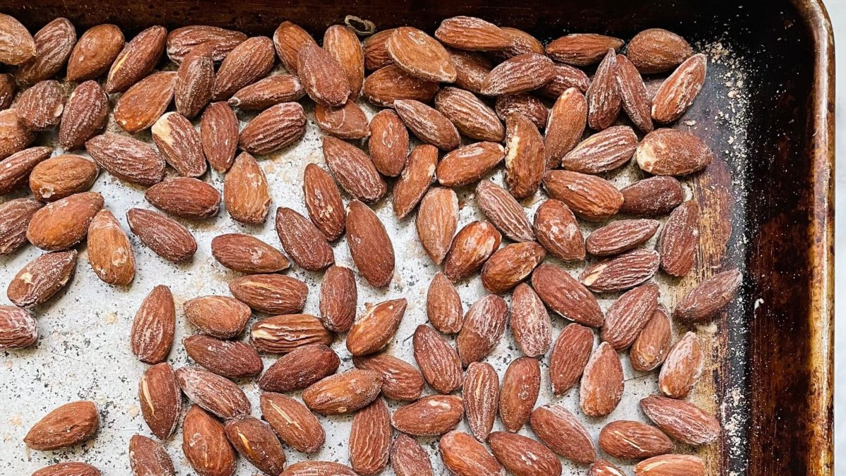 Raw almonds in a small bowl next to a pinch bowl of kosher salt on a kitchen counter